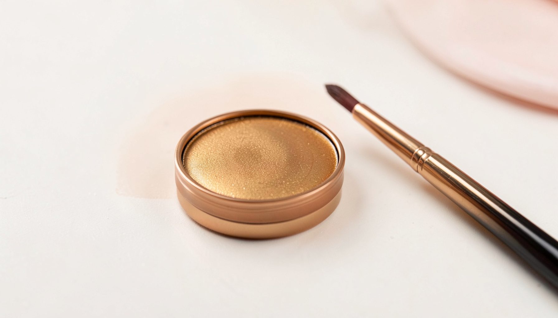 Pó bronzeador compacto em tom dourado quente sobre uma superfície clara, com pincel de maquiagem ao lado, atmosfera suave de beleza